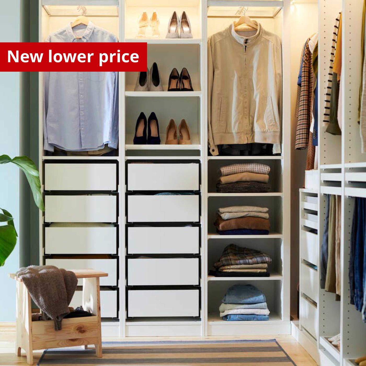 A white PAX wardrobe stands partly open. There are clothes hanging from a rail, drawers, shelves and a basket inside.