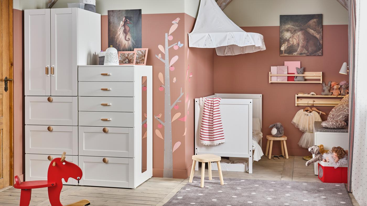 A white/pink traditional children’s room with SMÅSTAD/PLATSA storage, a SUNDVIK cot, and FLISAT children’s stools.