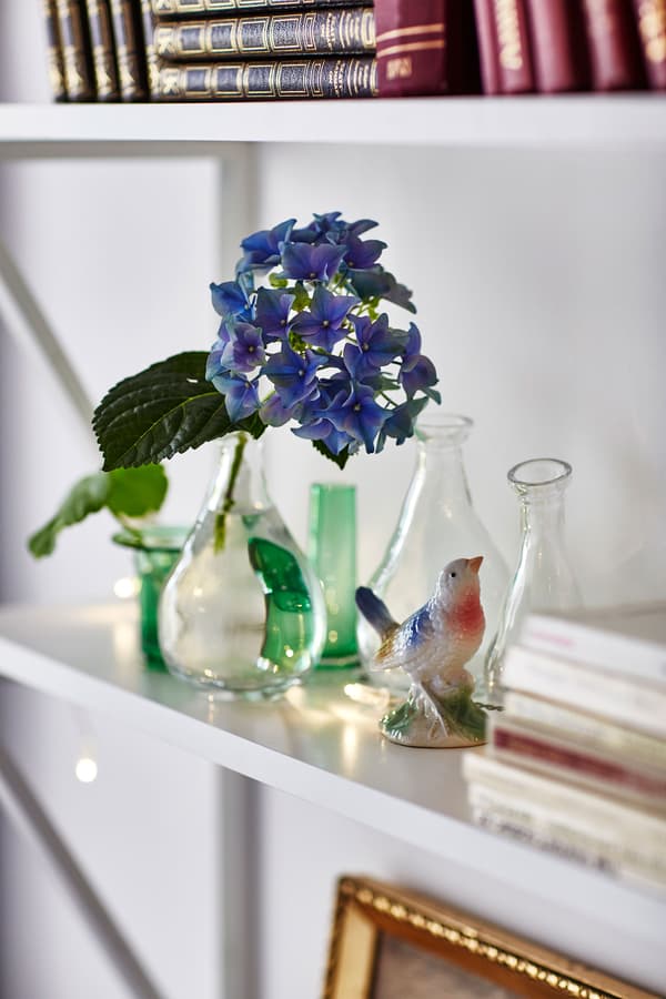 A white shelf is decorated with small glass vases and a figurine of a bird.