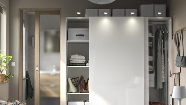 A white wall closet with many shelves for organizing and clothes hanging.