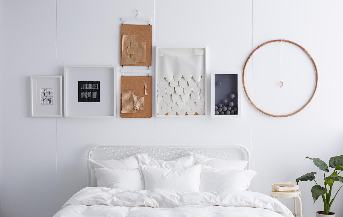 A white wall with frames and objects hanging above it in a straight line.