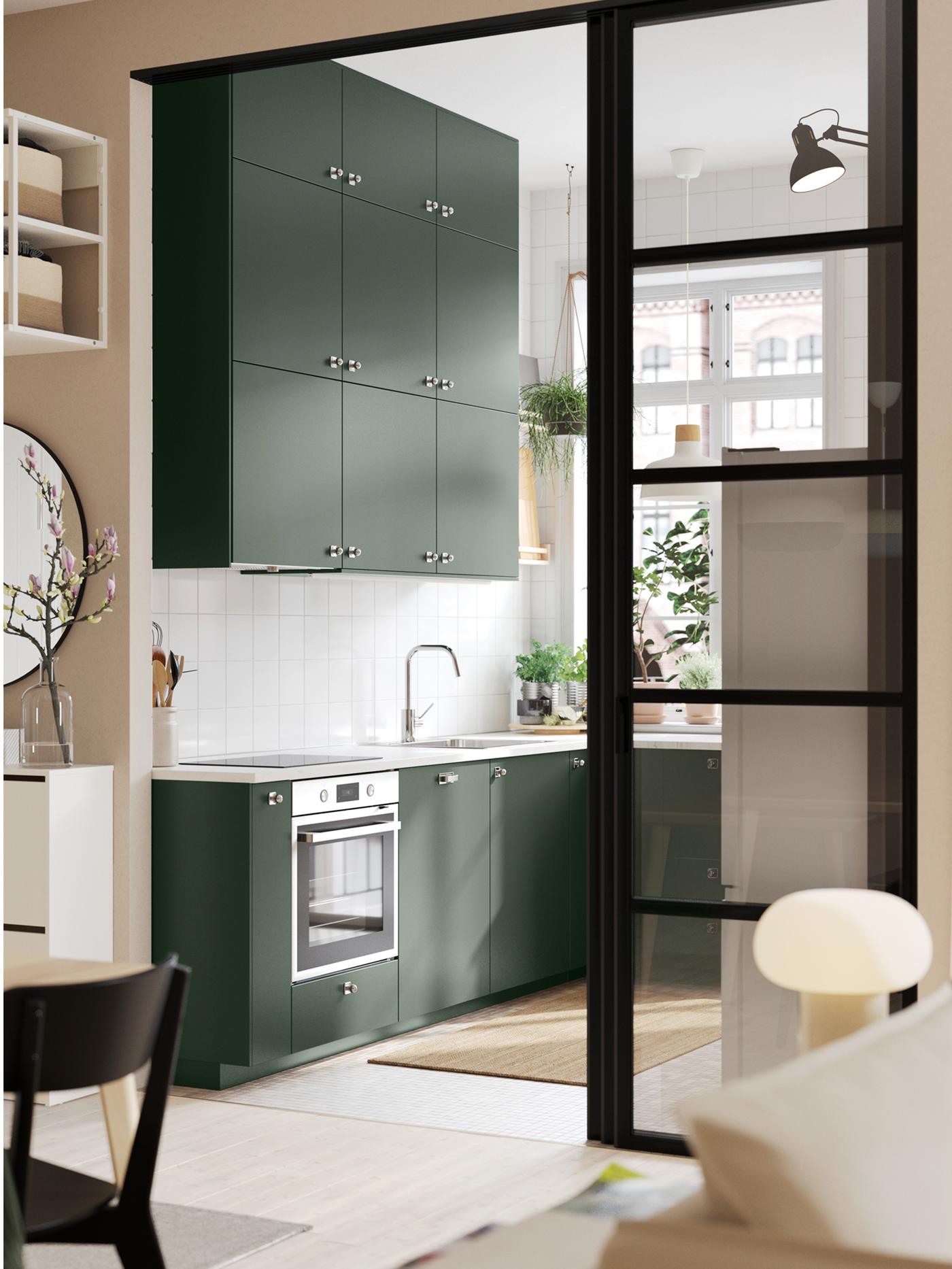 A wide doorway into a kitchen with deep green HAVSTORP kitchen fronts and a white marble effect/laminate EKBACKEN worktop.