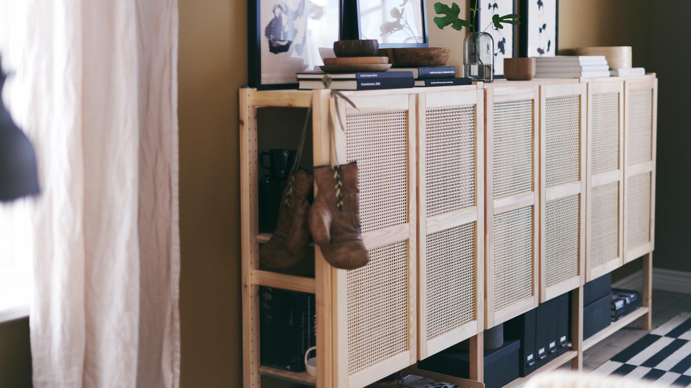 A wide IVAR cabinet combination with woven bamboo doors is styled with books, art and other personal objects.