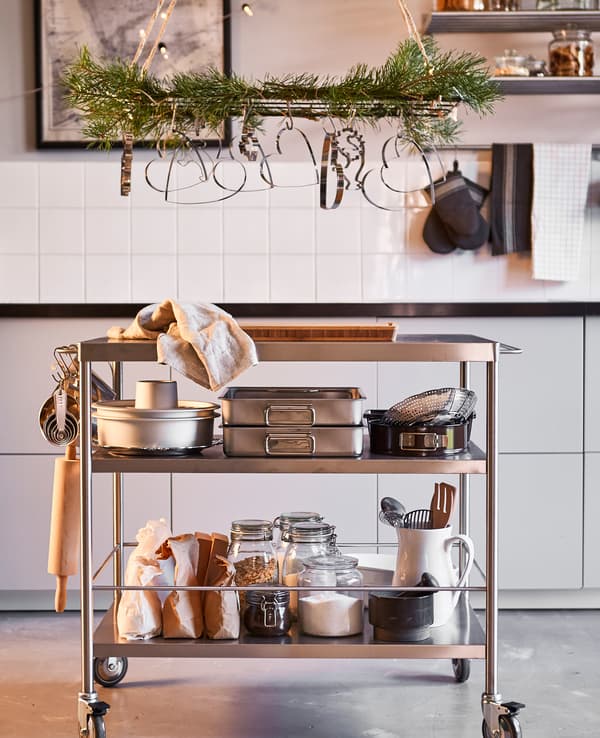 A wire trellis is hung above a kitchen island, decorated with greenery and cookie cutters.