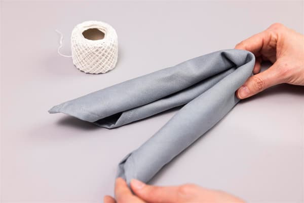 A woman folds the rolled-up napkin in half.