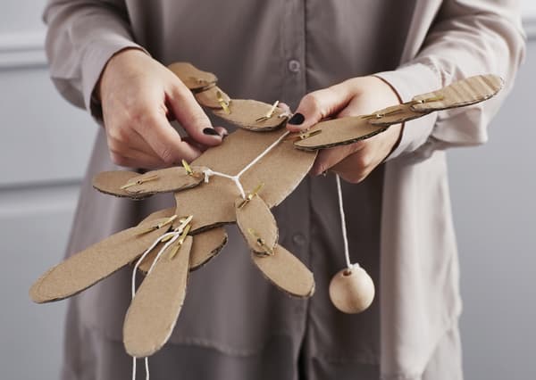 A woman holds a handmade cardboard toy.