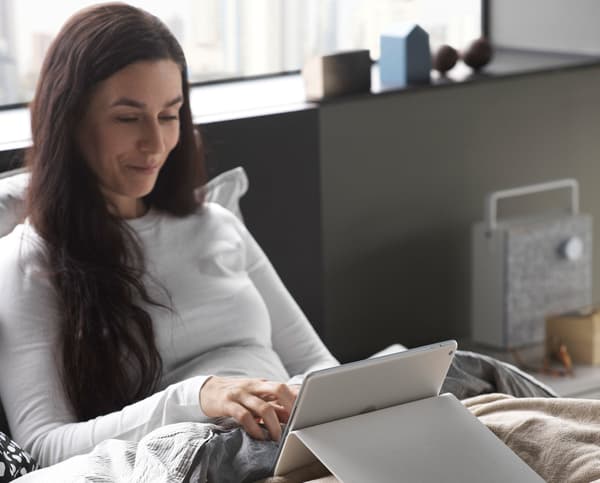 A woman looking at a handheld device in bed.