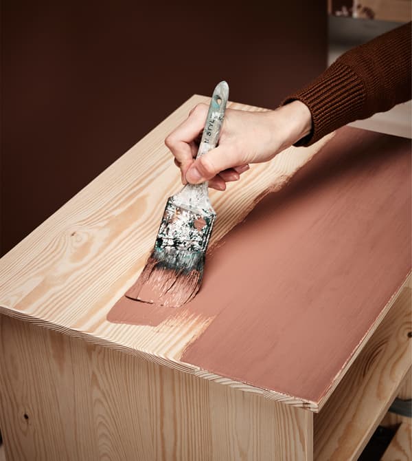 A woman paints a bedside table