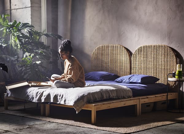 A woman sitting cross-legged on a bed in a warehouse.