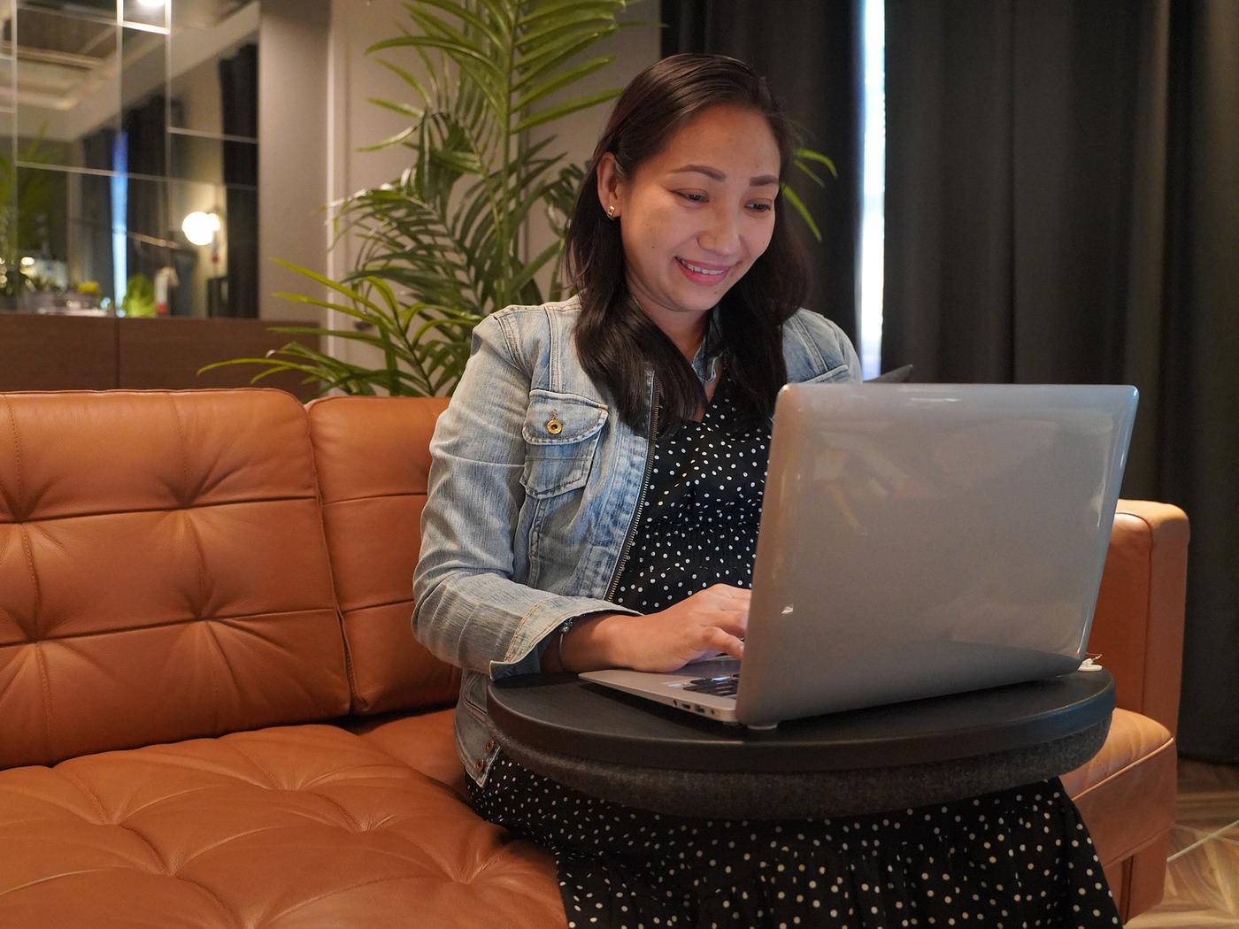 A woman sitting on a sofa with a computer.