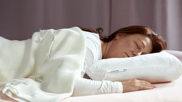 A woman sleeping on a low pillow on her stomach.