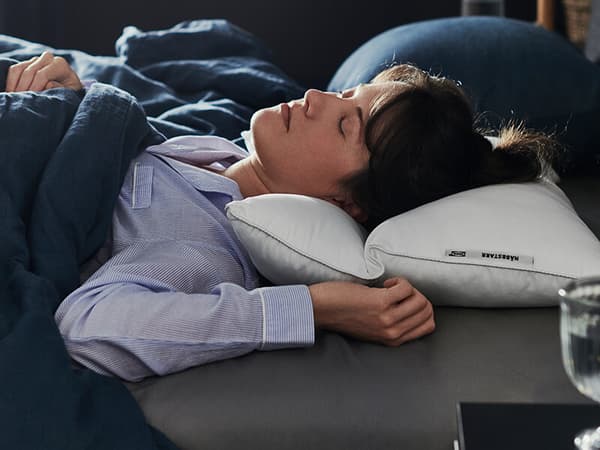 A woman sleeping on her back on a white pillow.