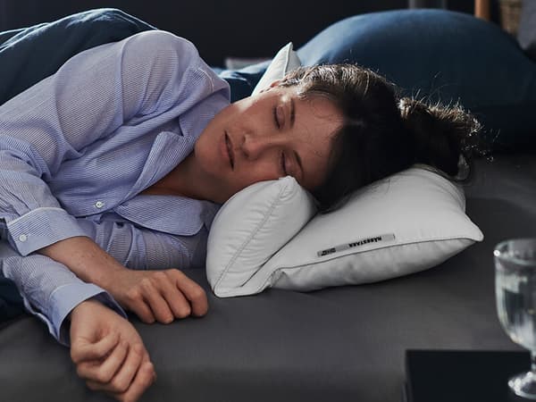 A woman sleeping on her side on a white pillow.