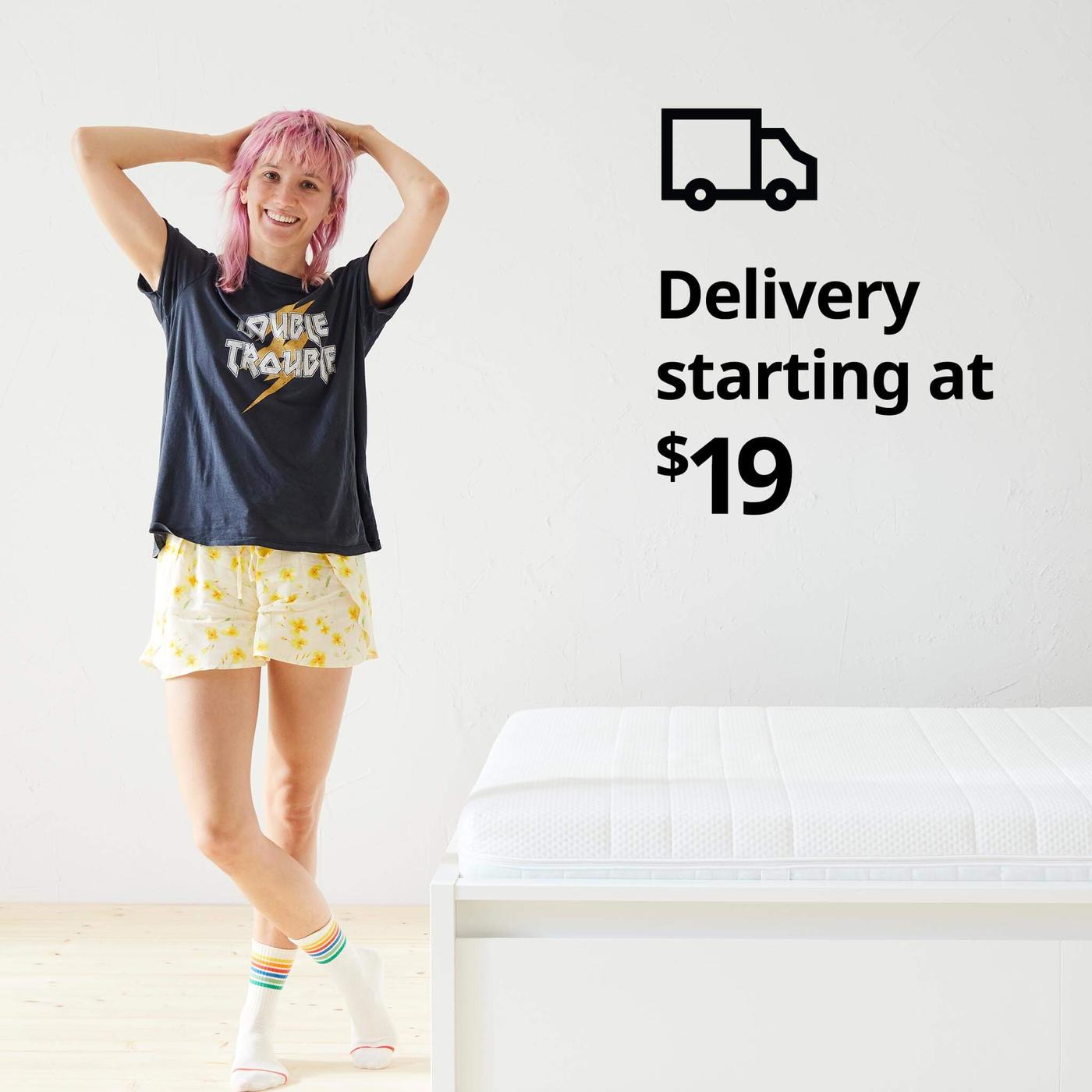 A woman standing in her pajamas next to a bed and a delivery truck symbol and the text 'Delivery starting at $19' on the image.