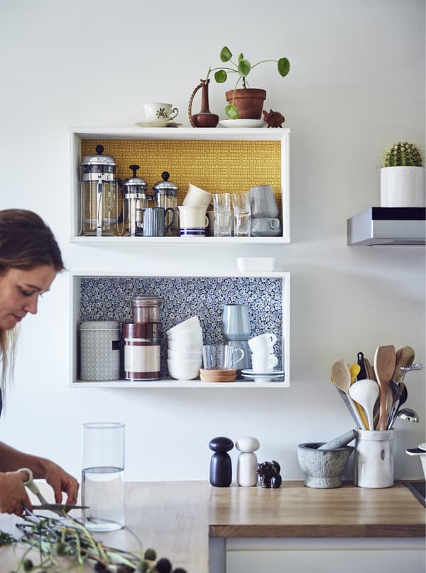A woman trimming plant stems in a kitchen.