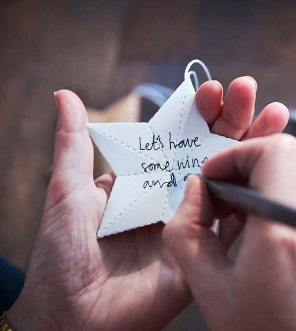 A woman writes a holiday wish on a paper star.
