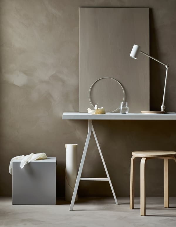A work area in a minimalist living room with a desk, chair and supplies hidden in a storage cube.