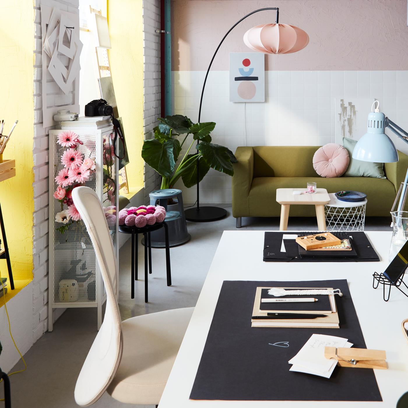 A workspace with a TROTTEN desk, a FLINTAN office chair and pink accents. At the back is a tall, curved floor lamp.