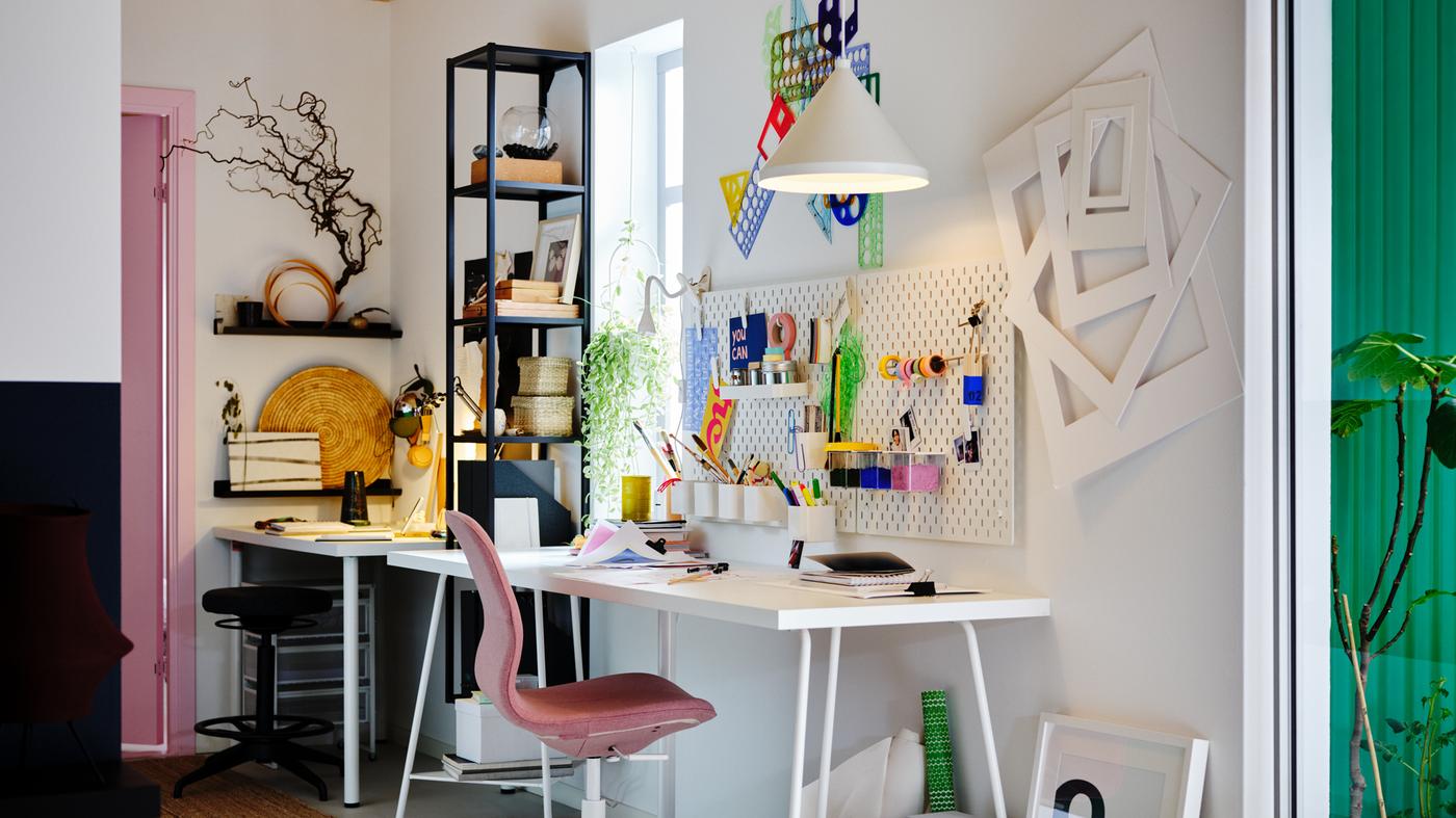 A workspace with a white LAGKAPTEN/TILLSLAG table, light brown-pink LÅNGFJÄLL office chair, plus white pegboards and pendant.