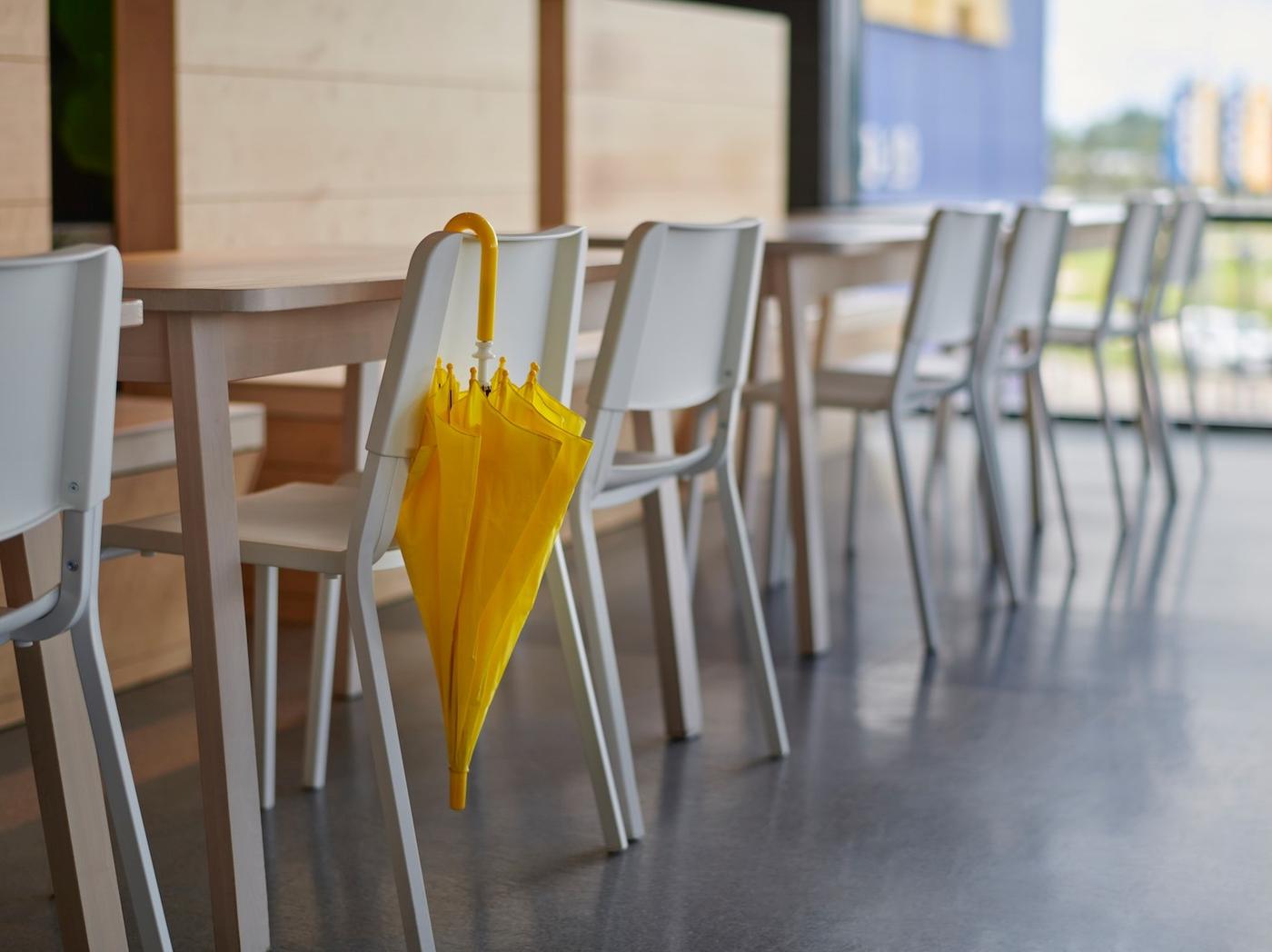 A yellow umbrella hanging on a chair at an IKEA Swedish restaurant.