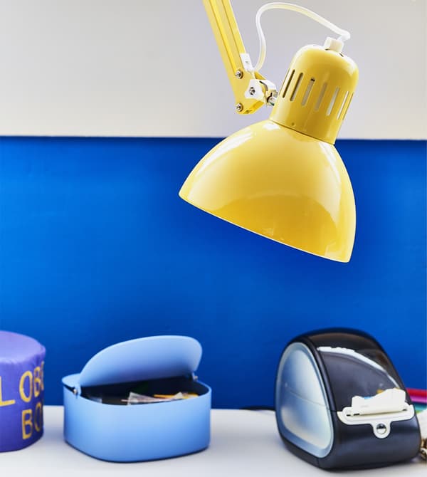 A yellow work lamp against a blue wall.