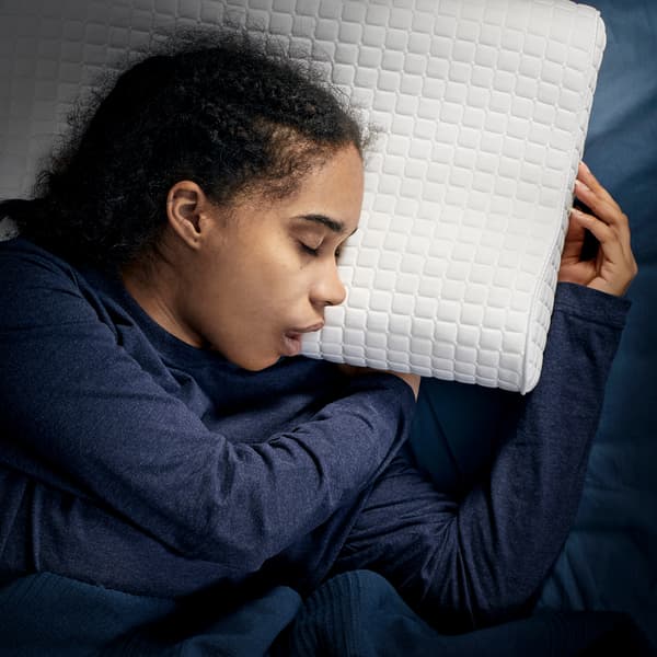 A young girl, laying on her side, is sleeping deeply on IKEA ROSENSKÄRM ergonomic pillow.