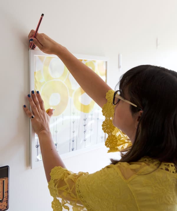 Abeer marking the corner of a picture frame on a blank wall.