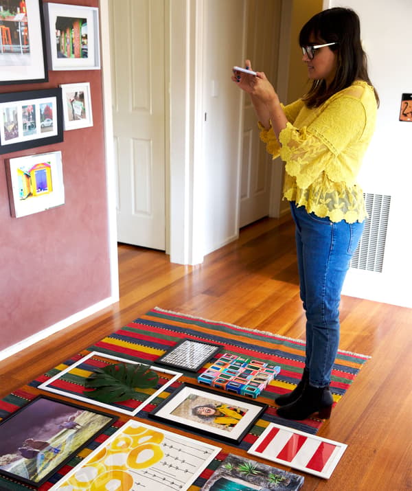 Abeer photographiant des cadres disposés sur un tapis.