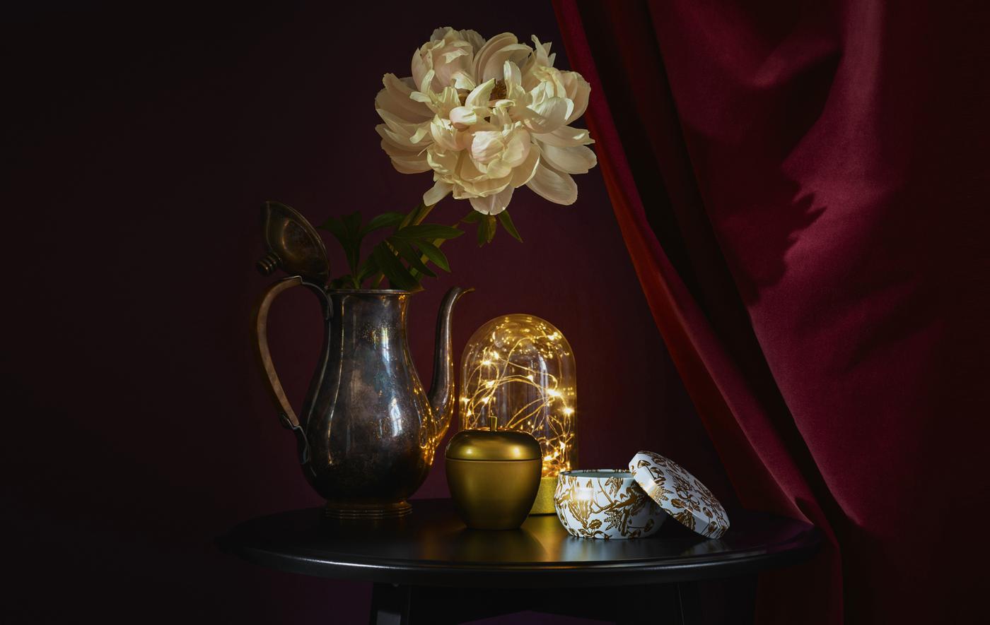 Accessoires et luminaires dorés sur une table ronde, sur fond rouge foncé.