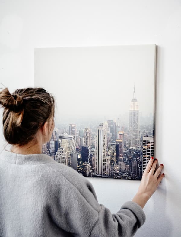 Agnes en train d’accrocher une reproduction représentant un paysage urbain