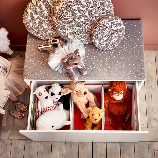 Almacenaje gris con cajones con peluches de oso, perro, mono y más en su interior.