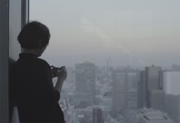 امرأة تلتقط صورةً لمنظر في المدينة من خلال نافذة.