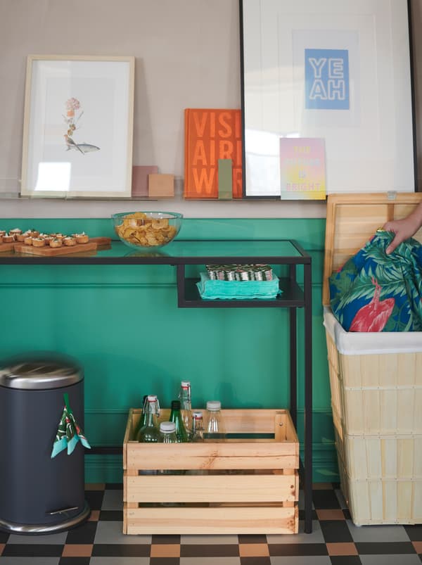 An ad hoc recycling station by a snack table: napkins in a MJÖSA bin, bottles in a KNAGGLIG box, laundry in a BRANKIS basket.
