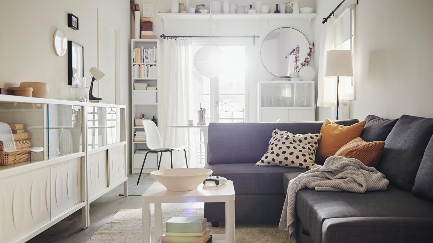An airy, light living room with a FRIHETEN sofa-bed with textiles and side-by-side white KALKNÄS cabinets with sliding doors.