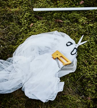 An animated GIF of a lacy curtain being draped over a pole, secured and cut into strips for a DIY wedding photobooth