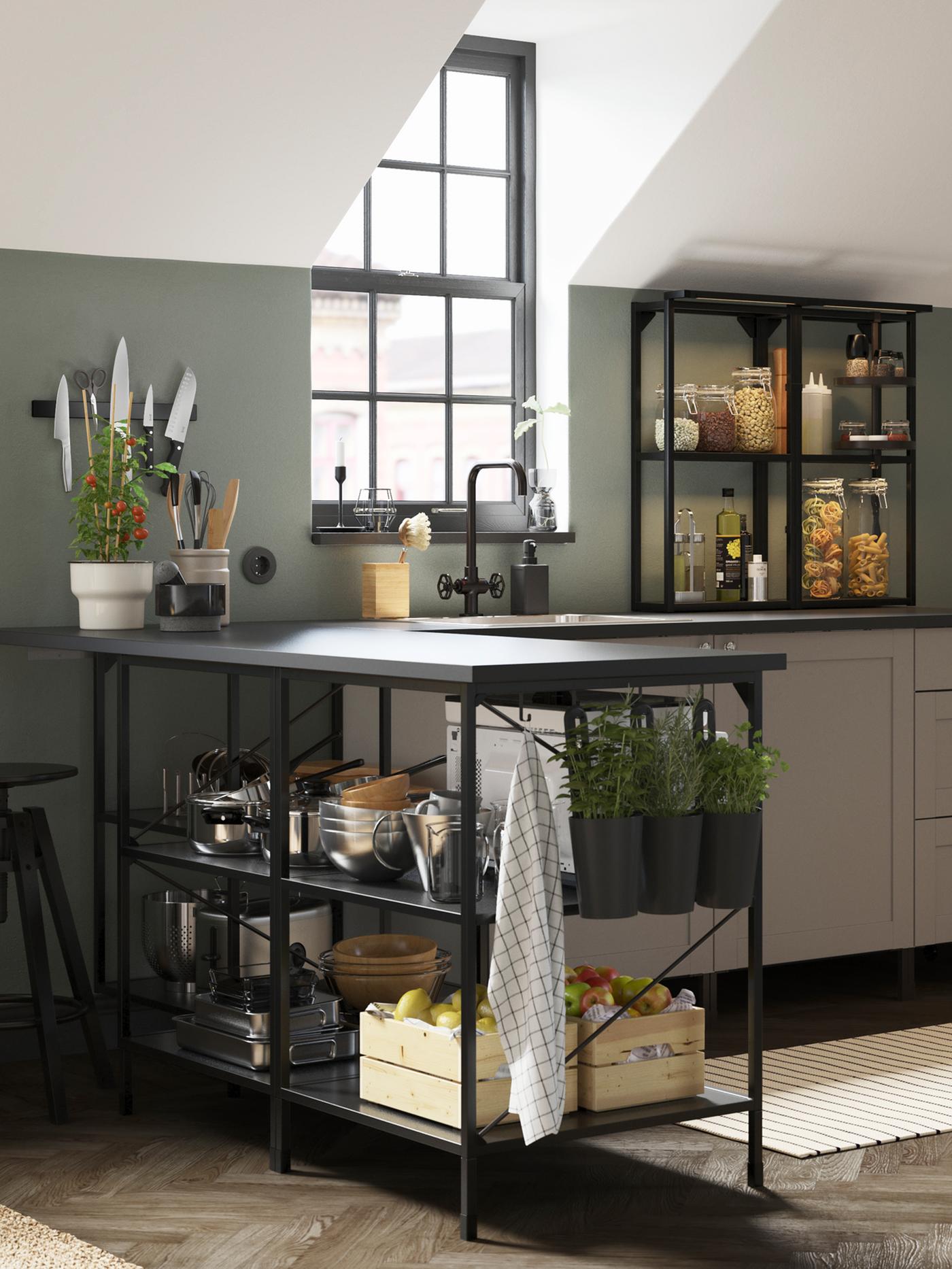 An anthracite/grey corner kitchen with a window on the back wall, a striped rug, and black containers with fresh herbs.