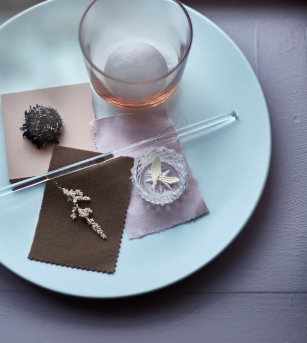 An arrangement on a plate with small flowers and textile pieces.