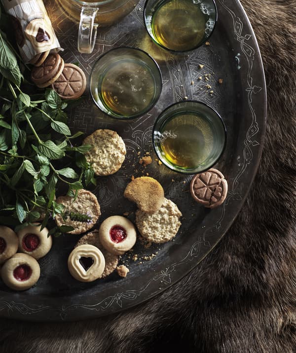 An assortment of biscuits and cups of tea arranged on a large tray.