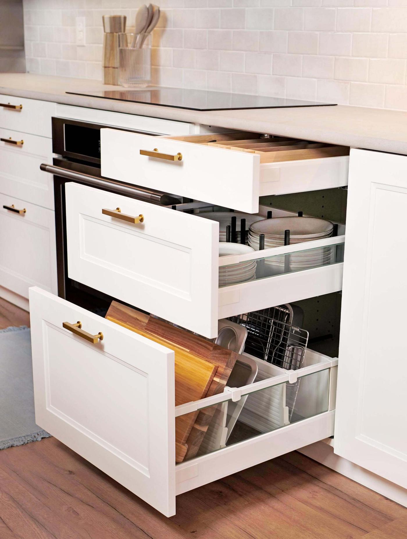 An AXSTAD kitchen with matte white fronts features two base cabinets, a tall wall cabinet, black appliances and a brown rug.