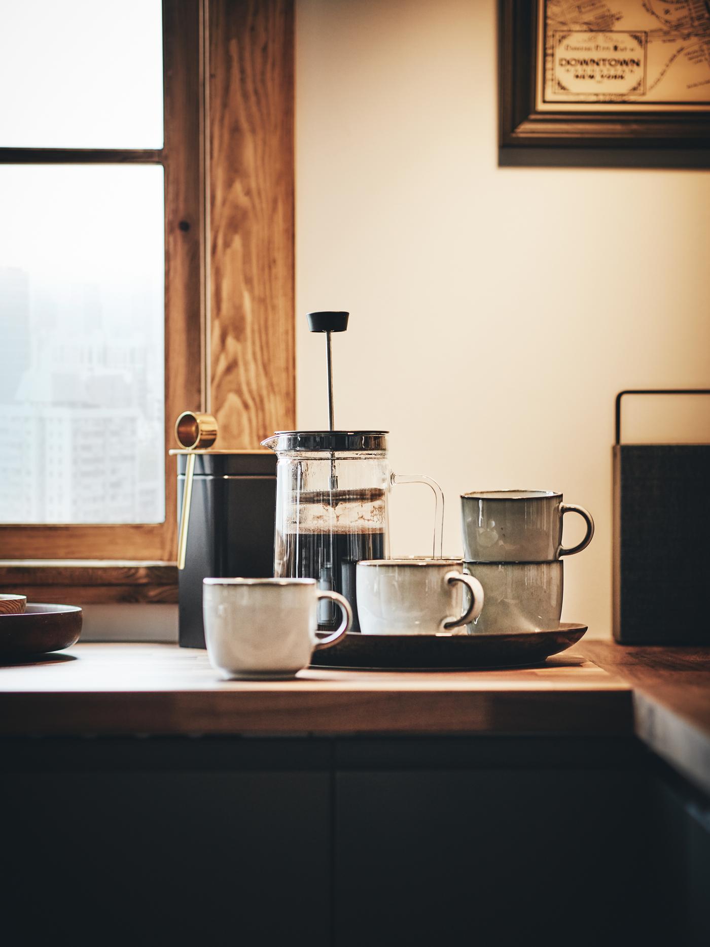 An EGENTLIG coffee/tea maker standing on a wooden worktop together with four mugs, in front of a window.