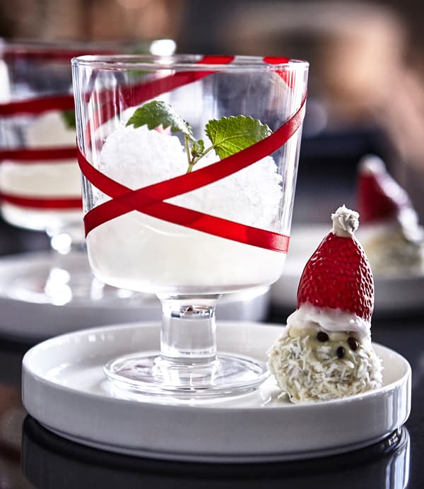An IKEA 365+ wine glass decorated with red ribbon and filled with a granita, next to a treat shaped like a snowman.