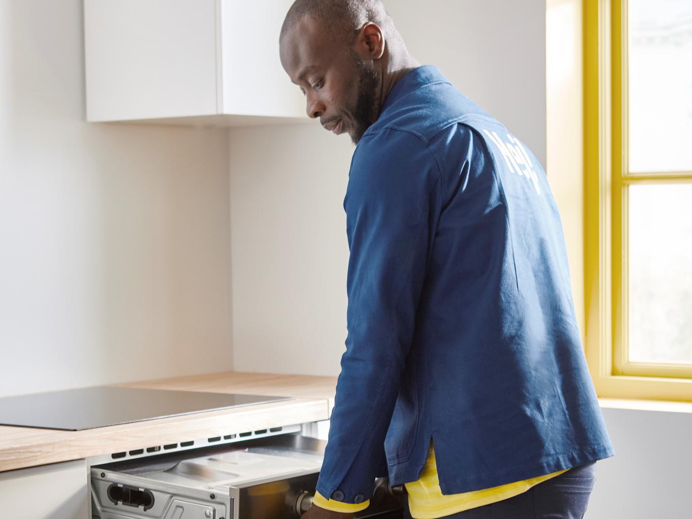 An IKEA co-worker connecting an electrical appliance in a kitchen.