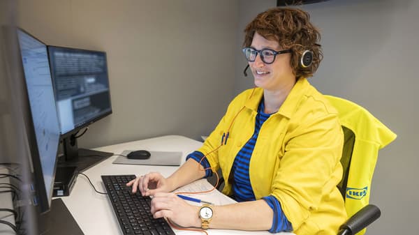  An IKEA co-worker in a yellow sweater helping a customer over the phone.