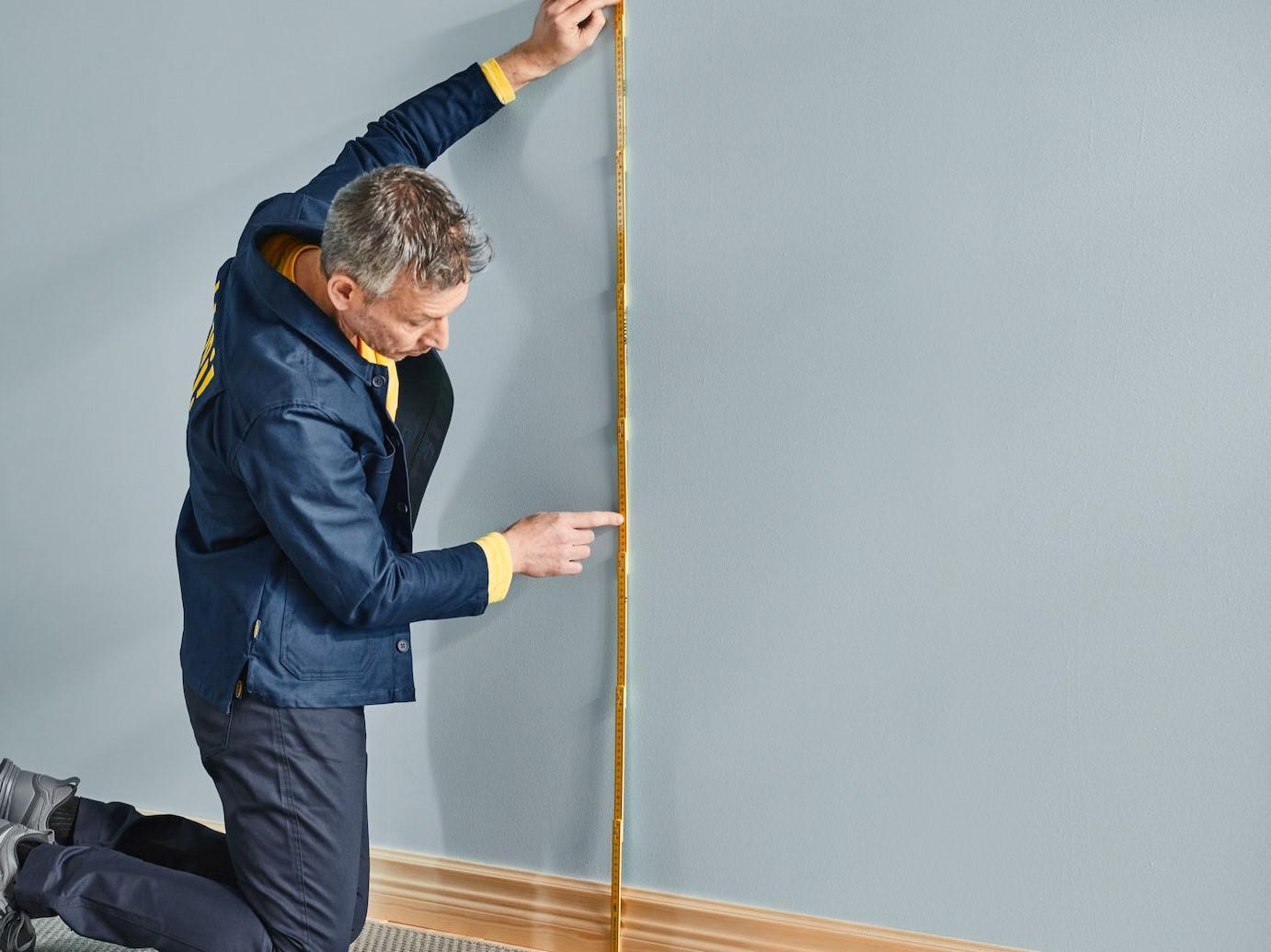 An IKEA co-worker measuring a wall using a yardstick.
