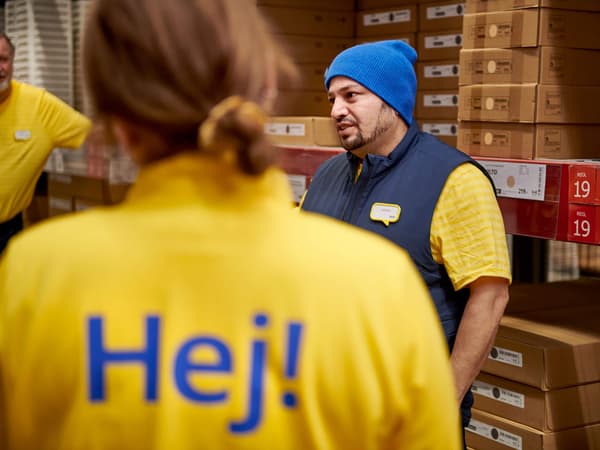 An IKEA co-worker wearing a yellow uniform with the word “Hej!” on the back of the shirt.