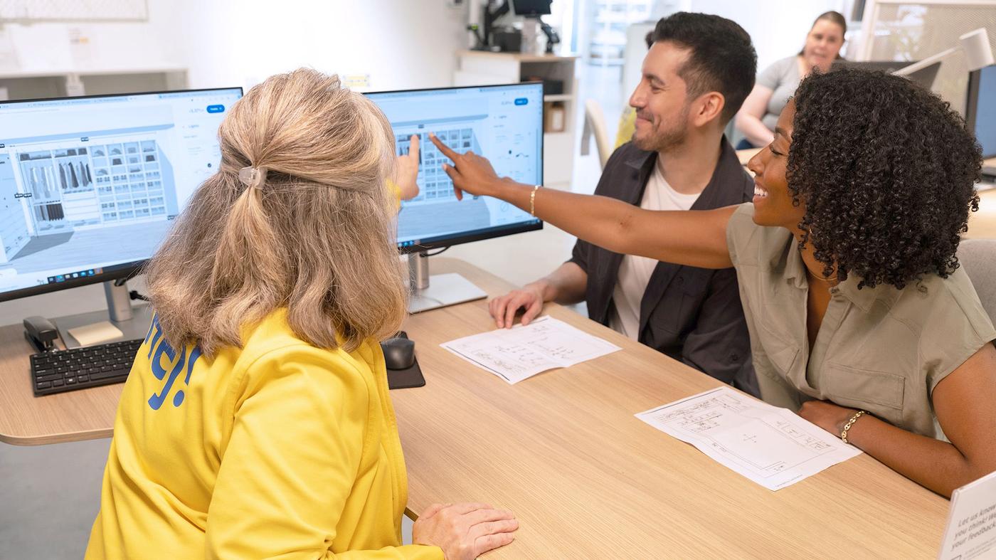 an IKEA coworker assisting two customers at a computer