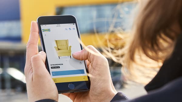 An IKEA customer looks at a STRANDMON armchair on her smartphone.