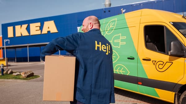An IKEA employee carries a parcel and an Austrian Post car is parked in the background