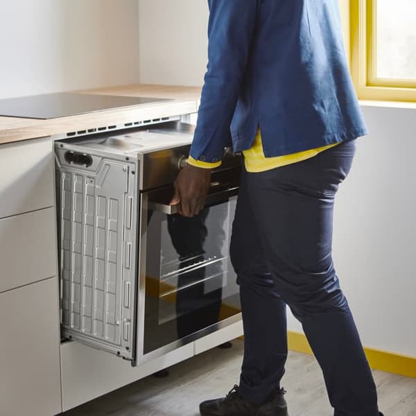 An IKEA employee dismantles an oven from a kitchen unit.