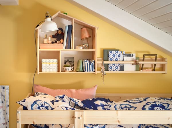 An IKEA FLISAT pine dollhouse mounted on a wall and used to store toys above a bunk bed.